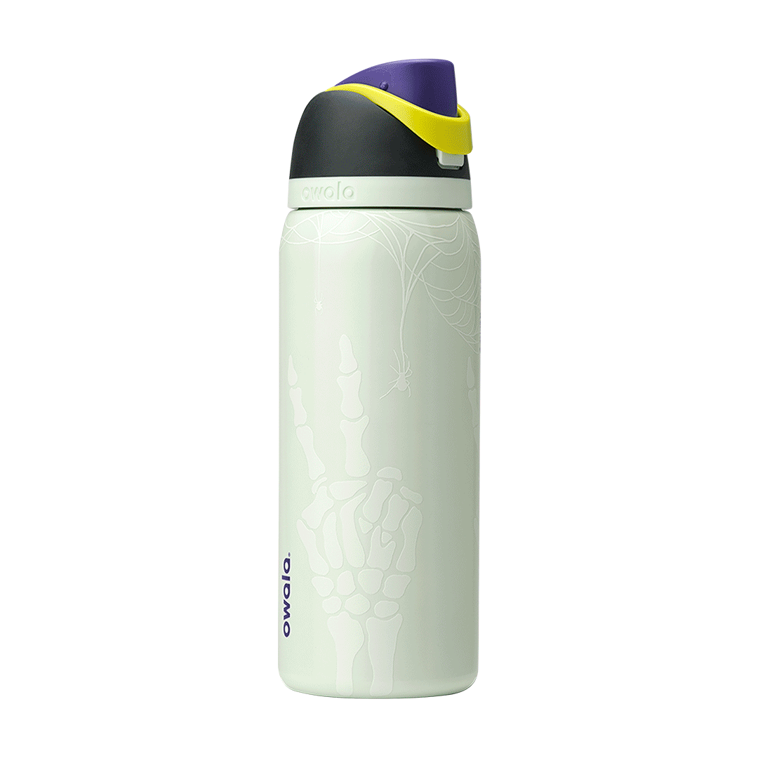 Owala FreeSip 32oz in RIP, pale mint insulated stainless steel body with white spider web, spider, and skeleton hand glow print, black lid, purple flip cap and yellow carry loop; glows in the dark
